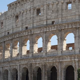 The exterior arches of the Colosseum against a blue sky